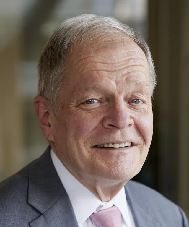 A senior missionary models appropriate jackets and suits and he smiles and talks to someone off camera.