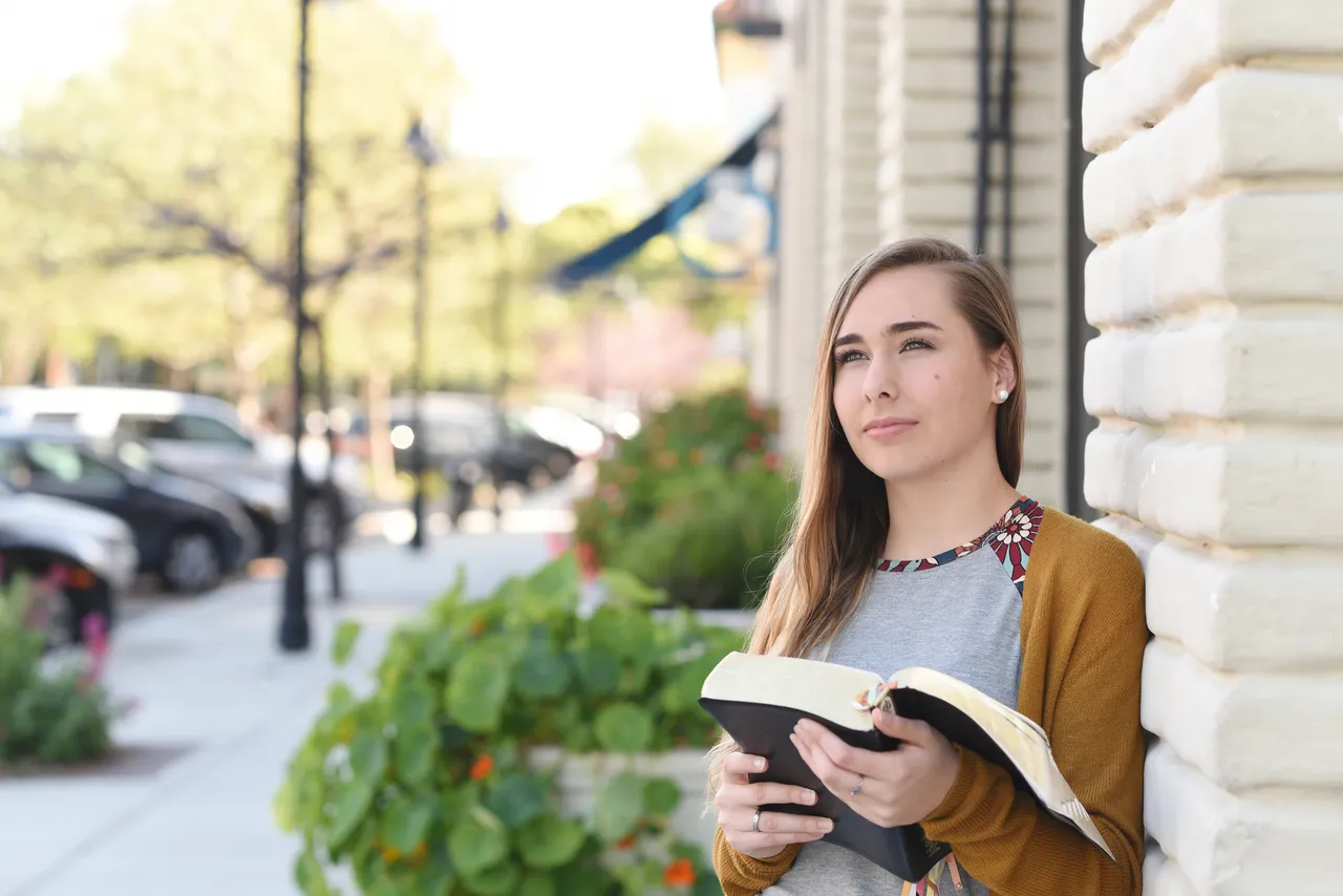 A young woman reads the scriptures and ponders