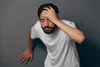 man leaning against wall holding head