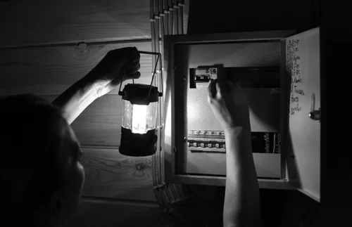 person with a lantern resetting a circuit breaker