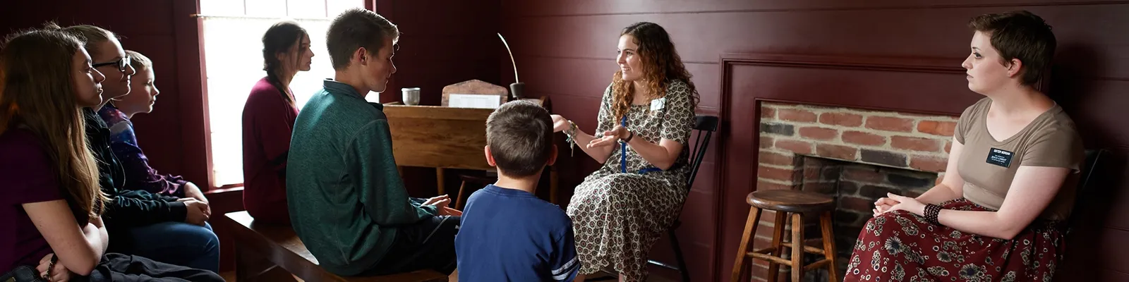 Various families sit together on benches. They are visiting historic sites and looking at artifacts.
