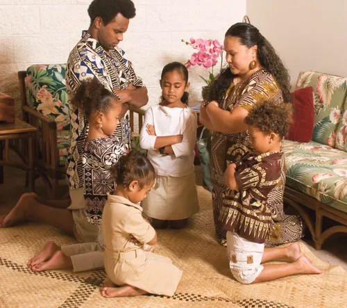 A Polynesian family kneeling in family prayer.