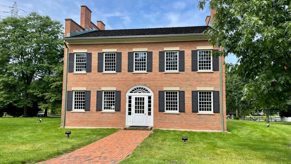 A large two-story, red-brick building with large, multi-paned windows and an arched doorway over the white door.