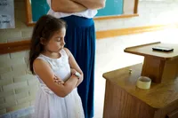 A young girl folds her arms in prayer as she prays in primary