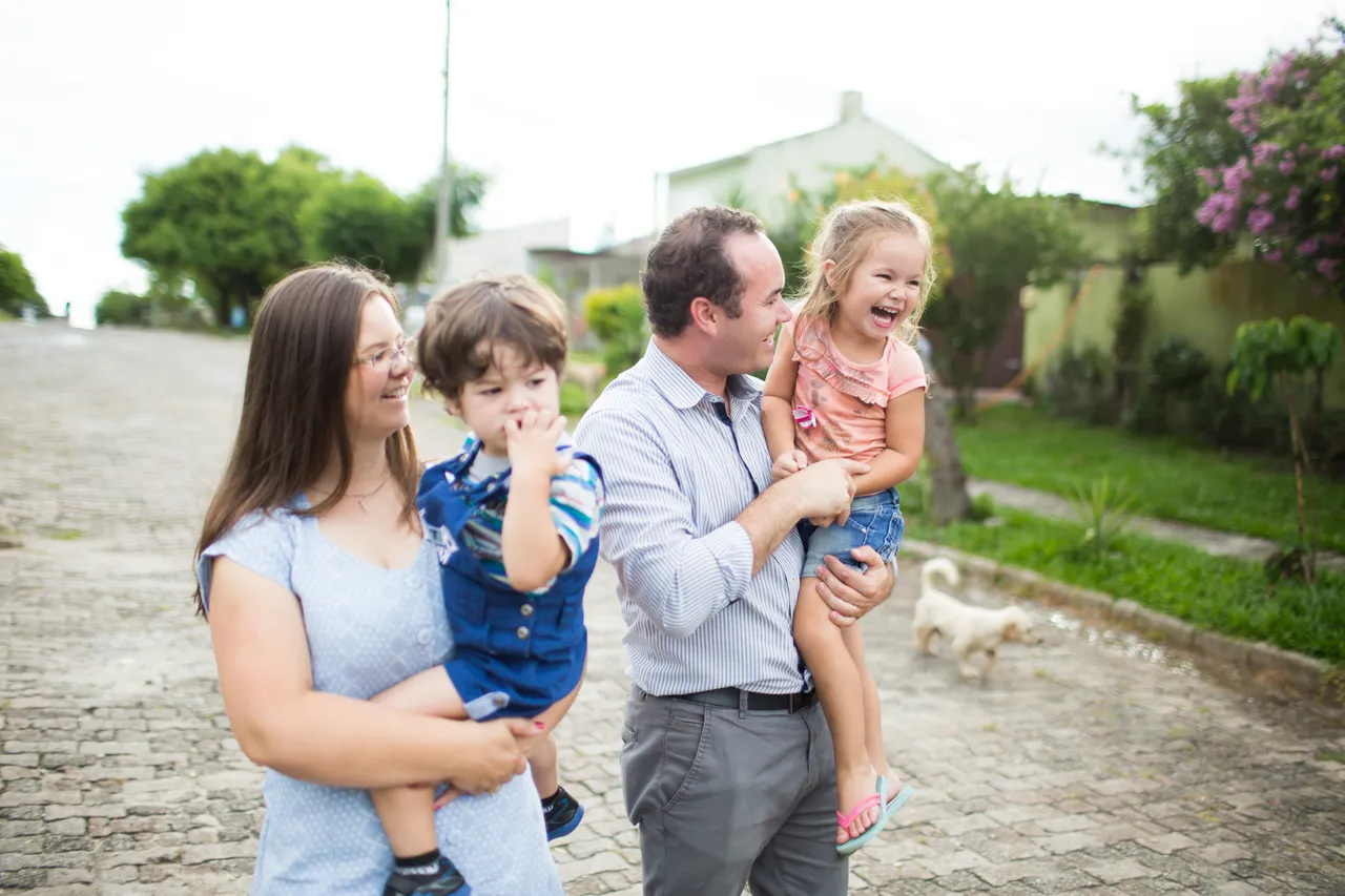 A young couple hold their children as they walk down a street