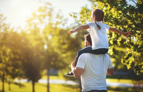 daughter sitting on her father’s shoulders