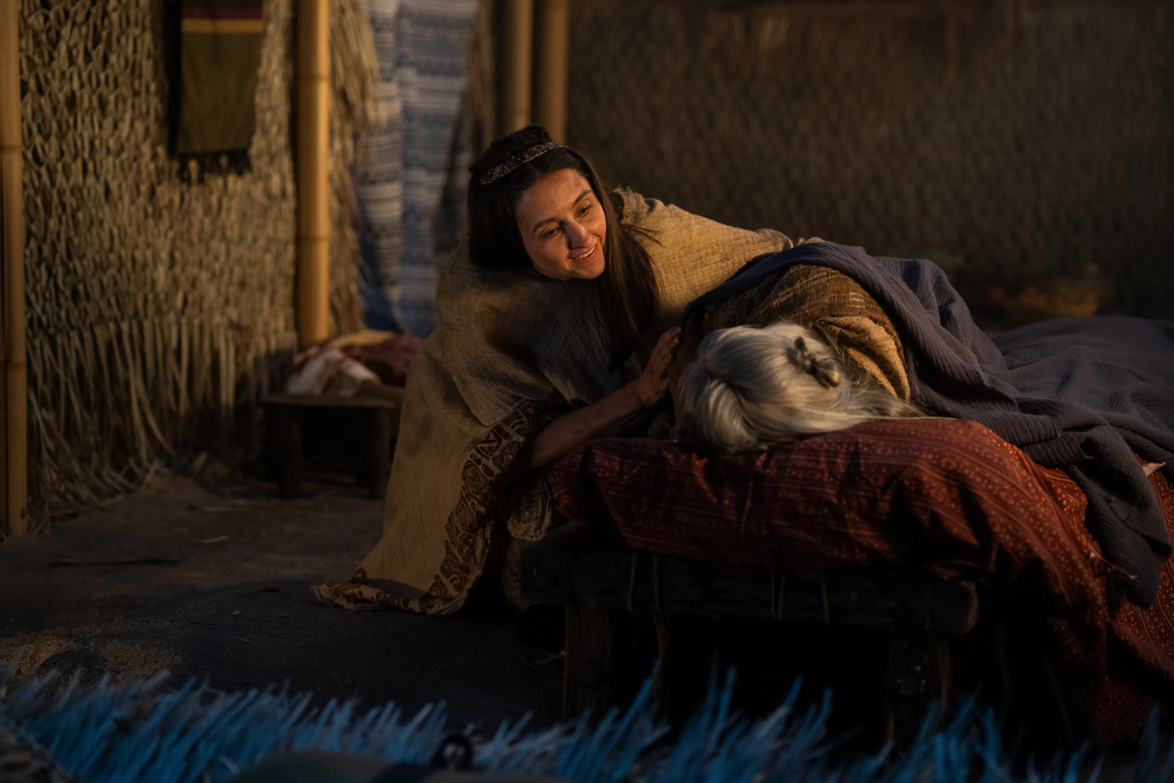 Alma's wife helps an elderly woman as she goes to sleep.