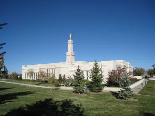 A full back view of the Monticello Utah Temple, surrounded by a walkway and green grass and trees.