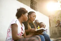 A daughter sits with her mother reading the scriptures