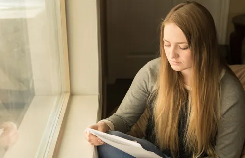 a woman reading next to a window