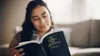 young woman reading a Spanish copy of the Book of Mormon