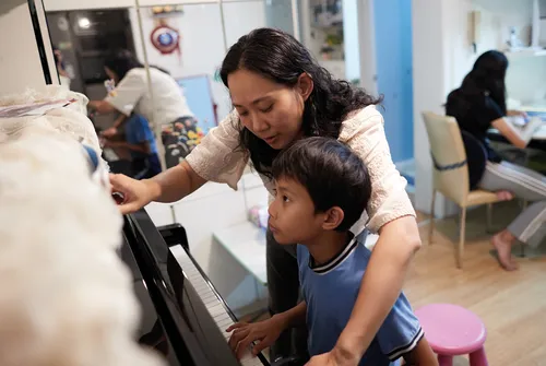 mother teaching child to play piano