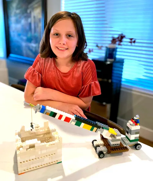 Girl with model of the temple made from plastic bricks