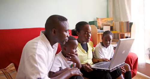 A family reading from a laptop computer.