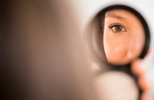 woman looking at herself in a compact mirror