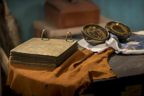 The brass plates sit open on a table next to the Liahona.