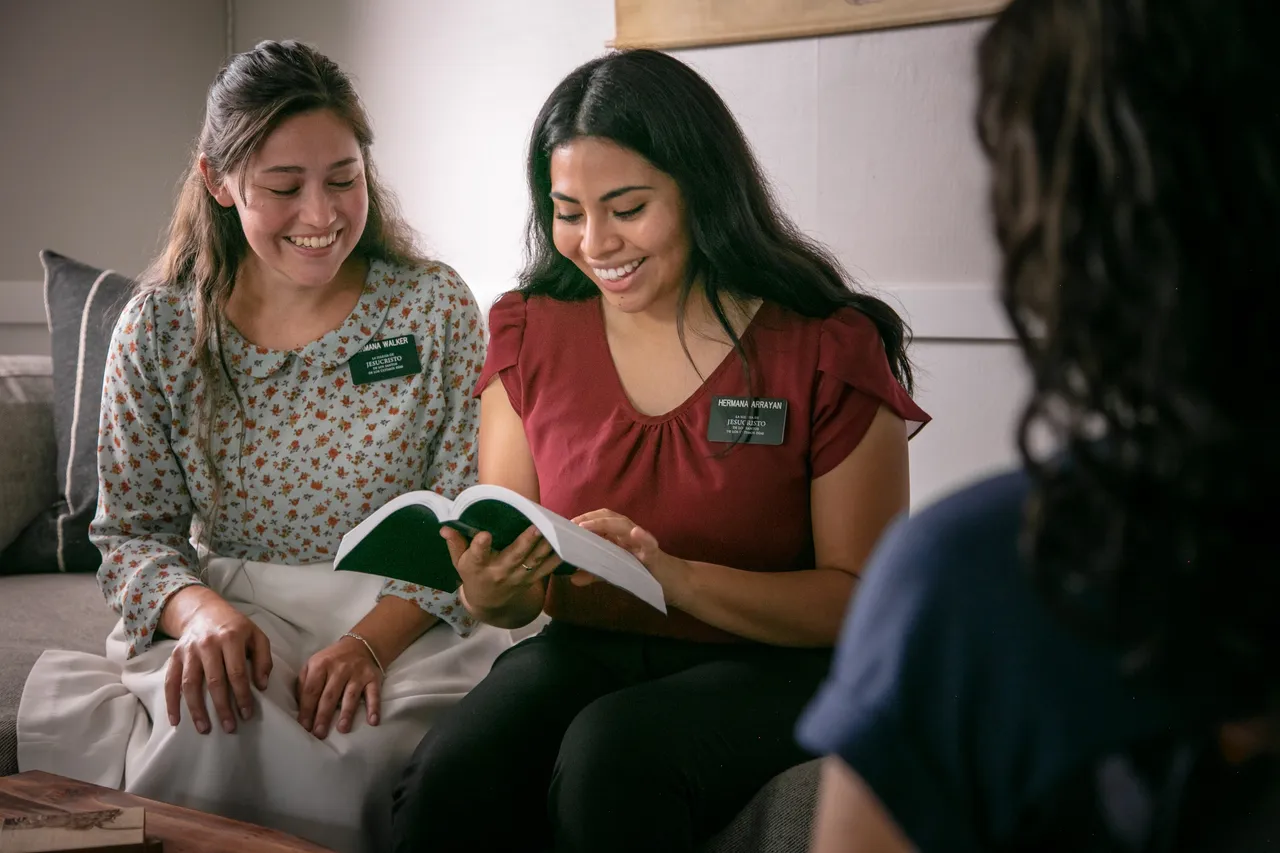 Missionaries reading to a woman from the Book of Mormon