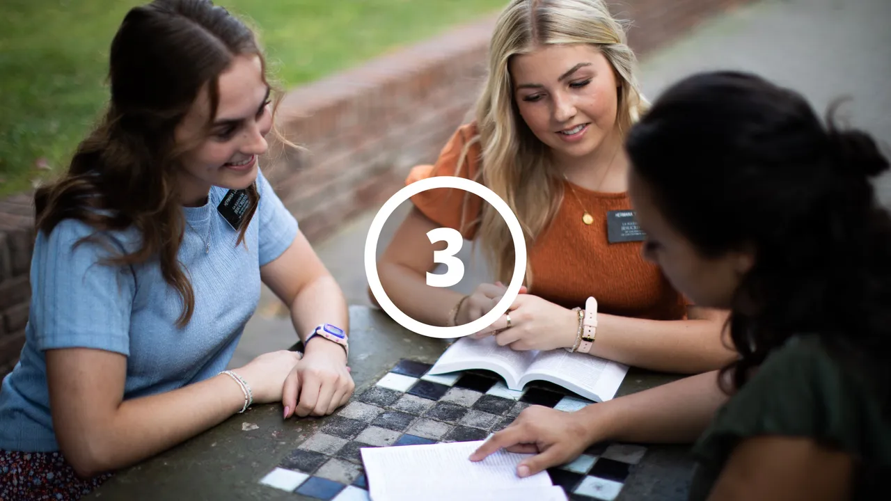 Missionaries reading to a woman from the Book of Mormon