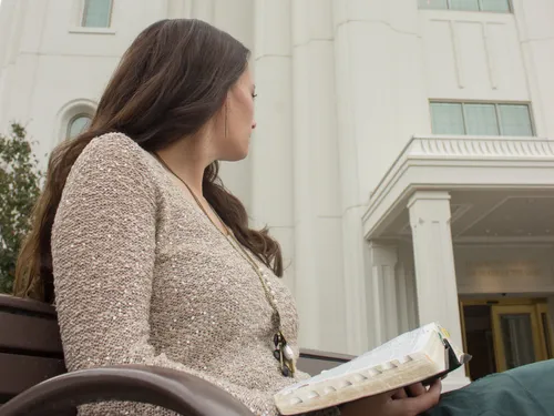 woman reading scriptures by temple