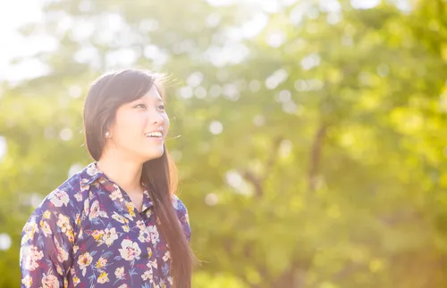 young woman smiling by trees