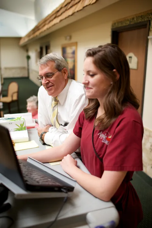 woman helping man at desk