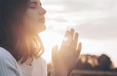 young woman closing her eyes and praying