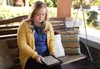 Woman on bench reading tablet.