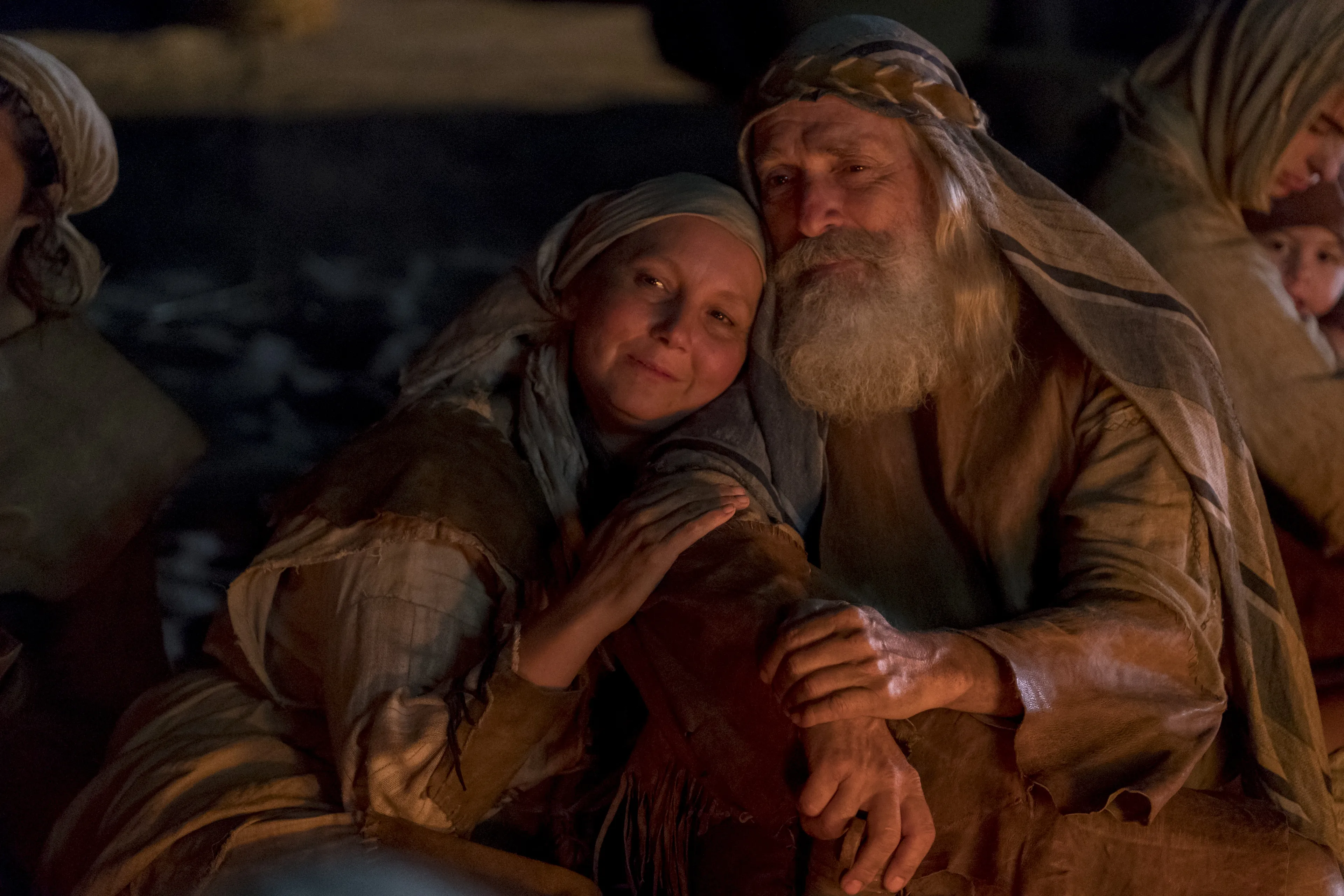 Lehi holds Sariah on the beach at night.