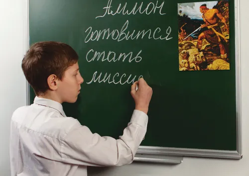 boy writing words on chalkboard