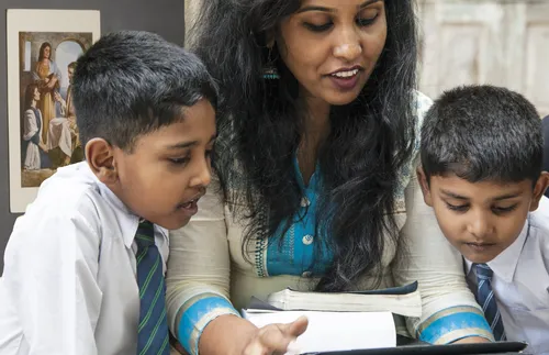 woman and two boys looking at tablet