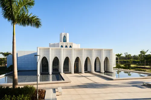 Exterior of the Brasilia Brazil Temple. It features the front of the temple, the entrance area, and trees nearby. Image was taken during the day.