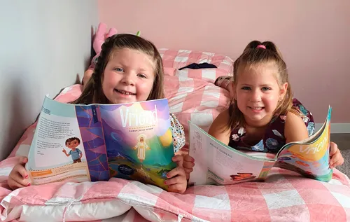 Two girls holding up copies of the Friend