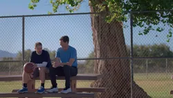 Two men talk on a bench after playing basketball