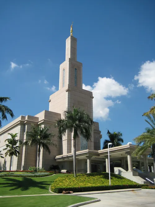 The entrance to the Santo Domingo Dominican Republic Temple, with a view of the angel Moroni on the spire and the trees on the grounds around the temple.