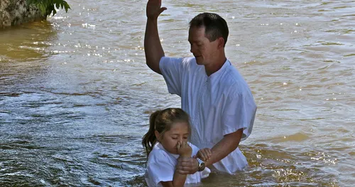 young girl being baptized by man