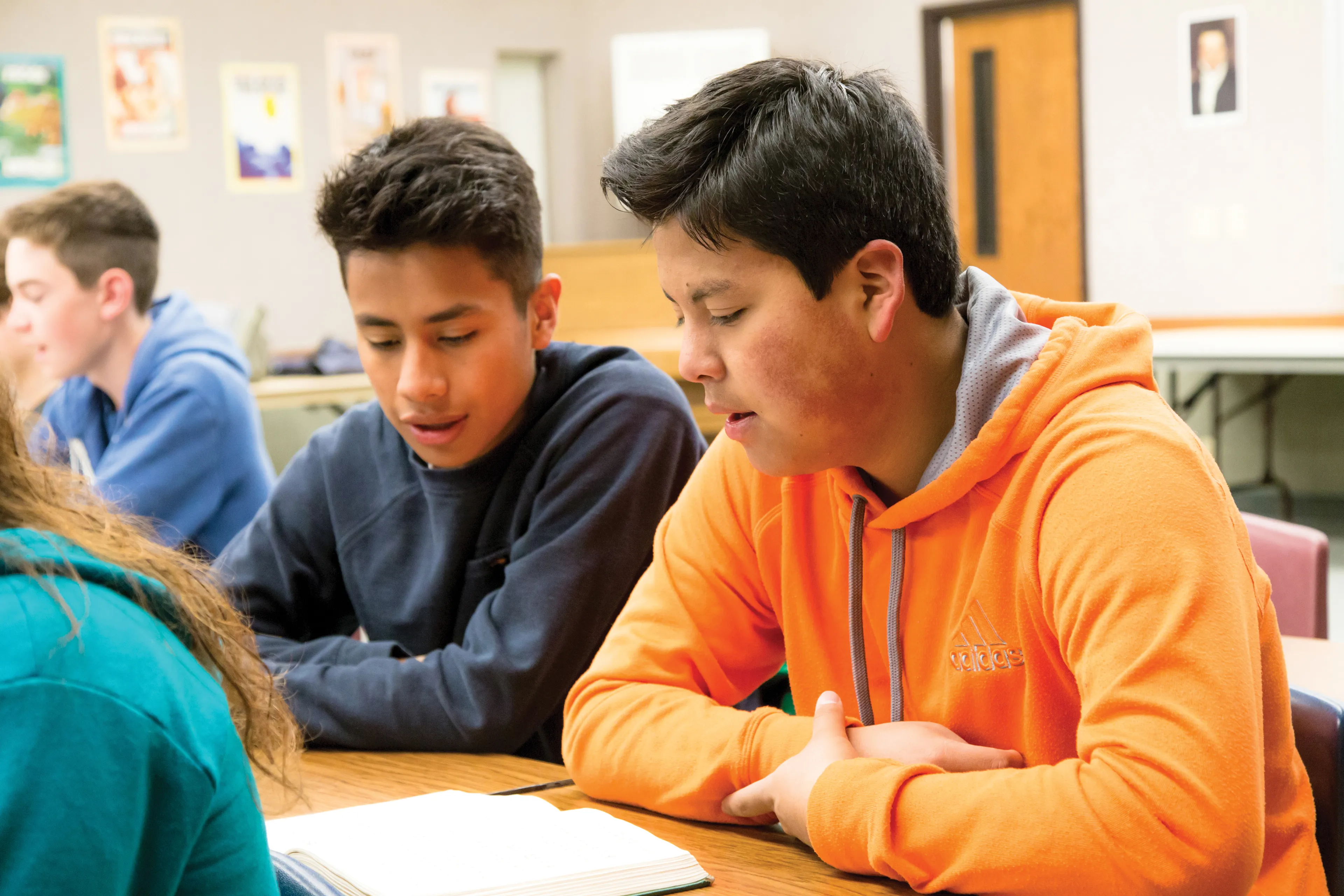 Two young men sharing a hymn book in a seminary class.