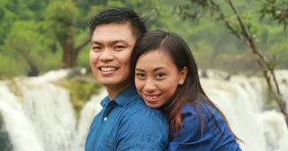 a couple posing in front of a waterfall