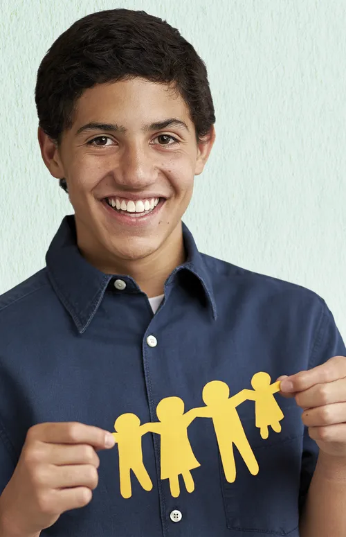 A young man holding up a chain of paper dolls.