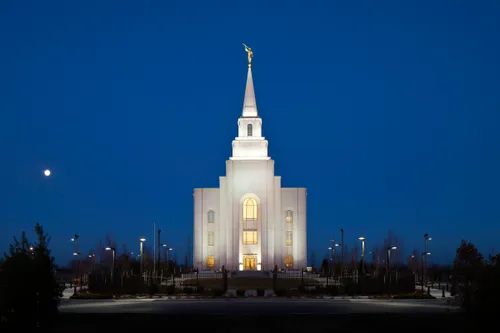 A front portrait view of the Kansas City Missouri Temple at night, illuminated by exterior lights.