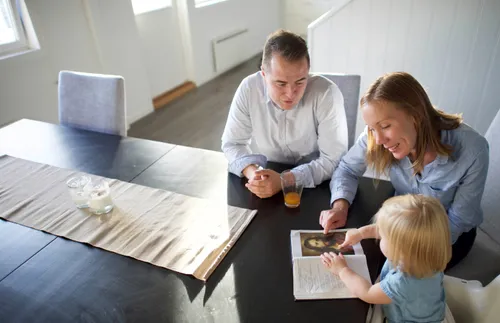 mother and father sitting together with their little girl looking at a book