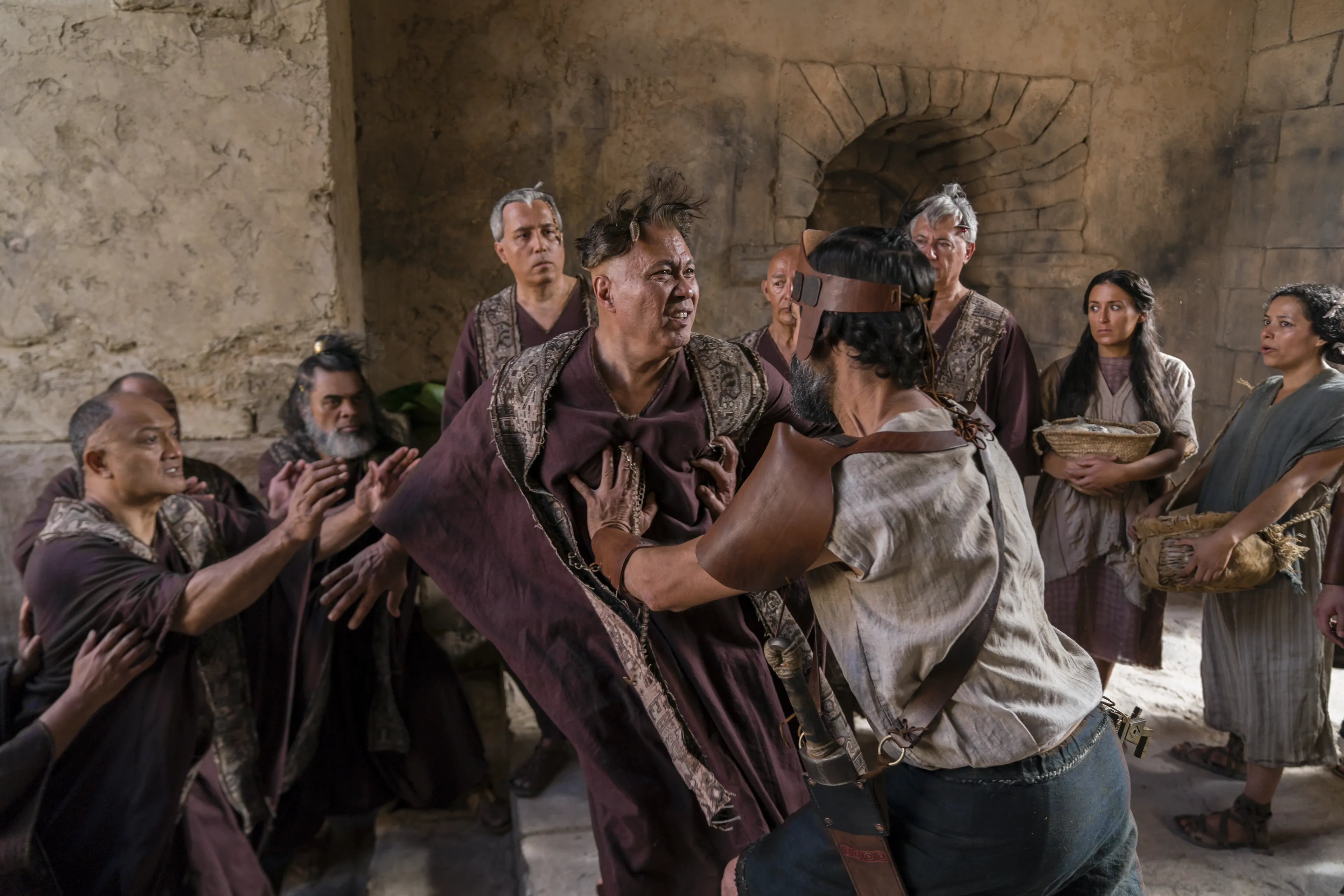 Older priests are stripped of priestly mantles and mocked by members of King Noah’s court.