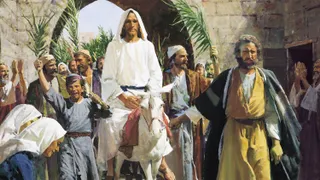 Jesus Christ in white robes riding on a white donkey. He is passing through a brick arch into Jerusalem. Numerous people are following Him. Some of which are waving palm leaves and laying cloth on the ground in front of Him.