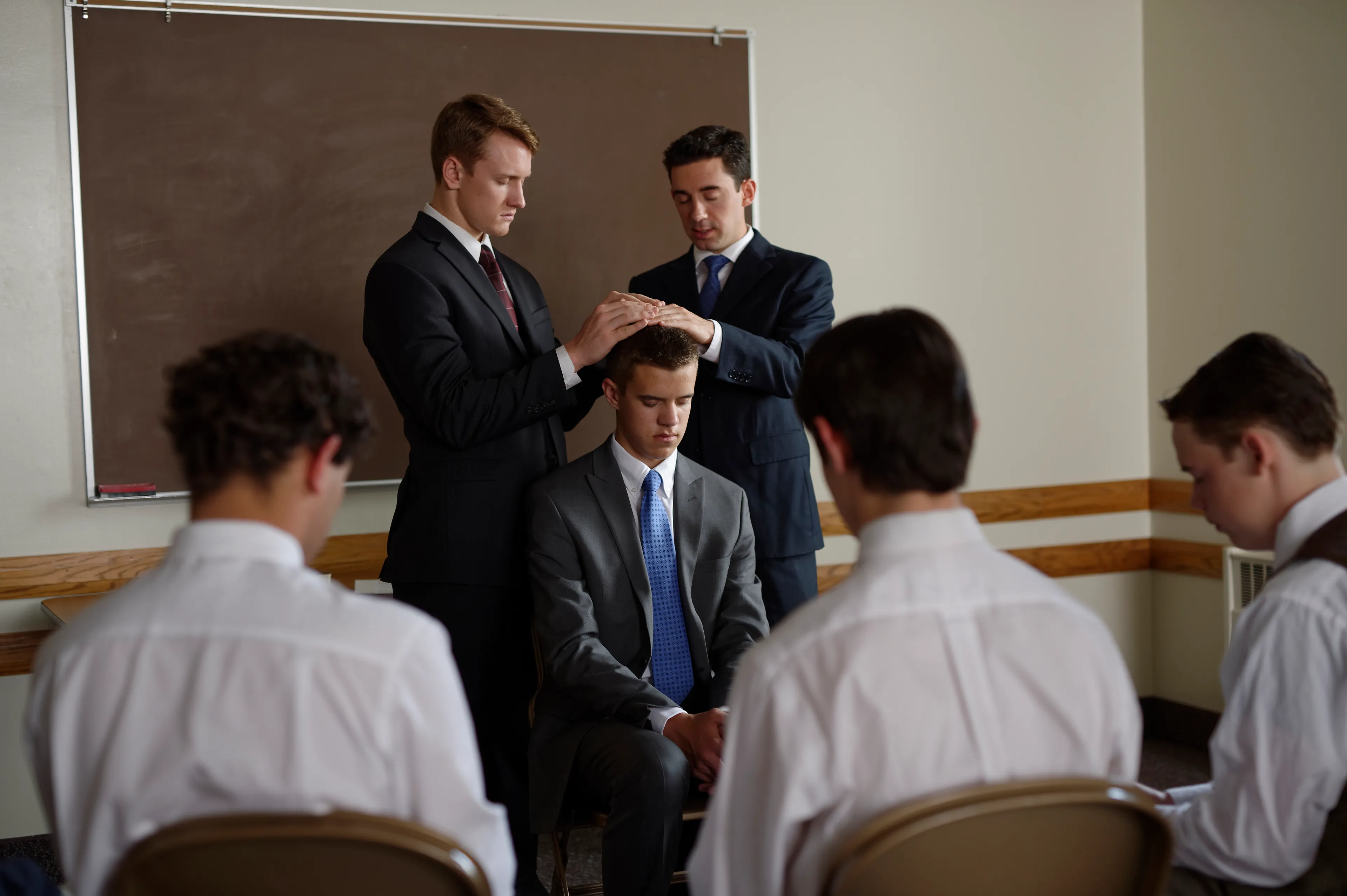 A young man being ordained to the priesthood through the laying on of hands.