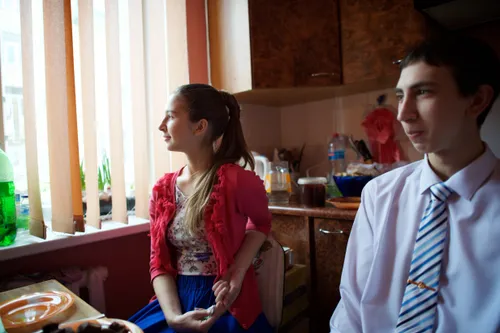 a young woman and a young man sitting at a table in a kitchen