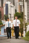 Two elder missionaries walking down a city sidewalk in Sao Paulo, Brazil.  There are buildings in the background.
