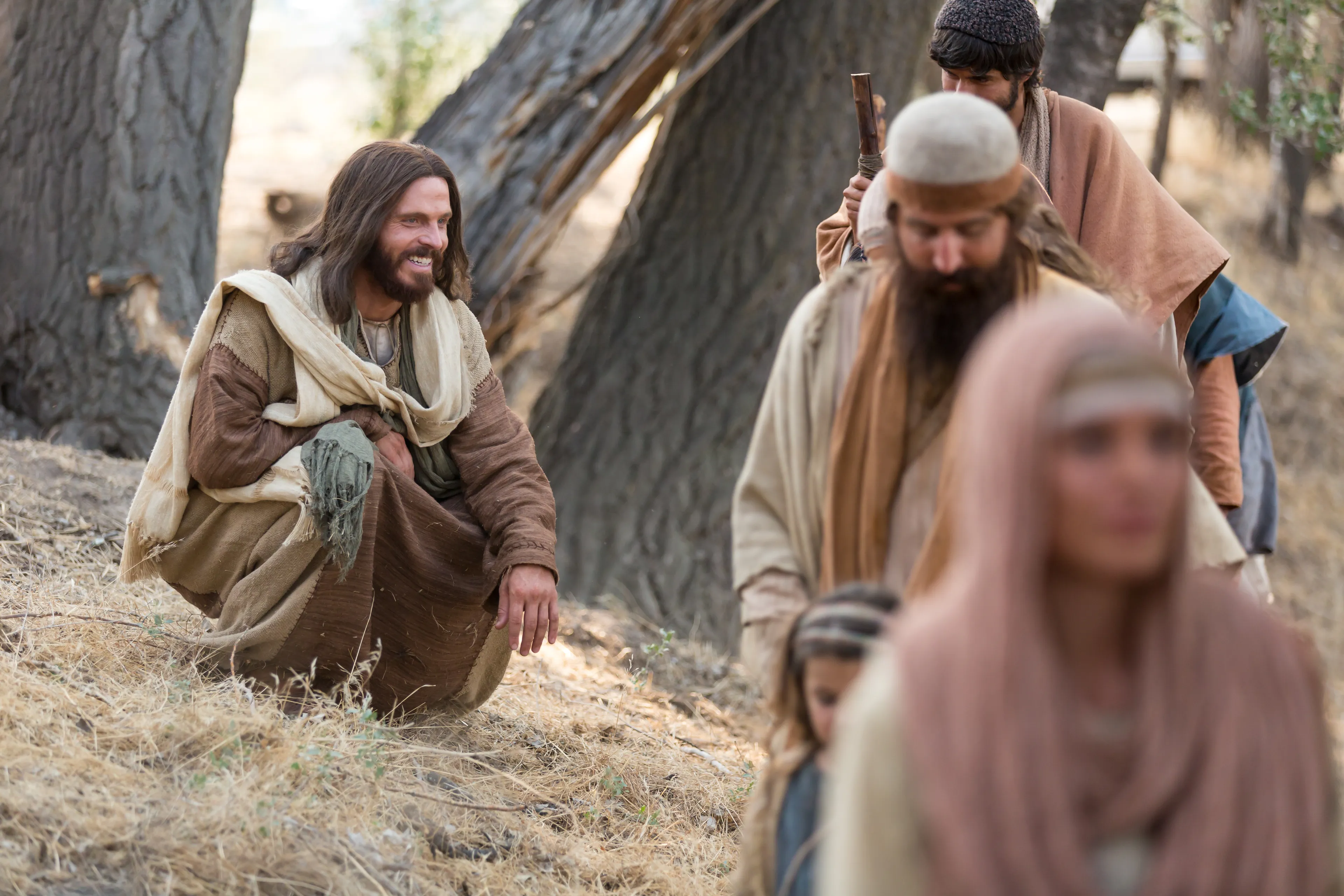 Portrait of Jesus smiling at a group of children and their parents as they pass by.