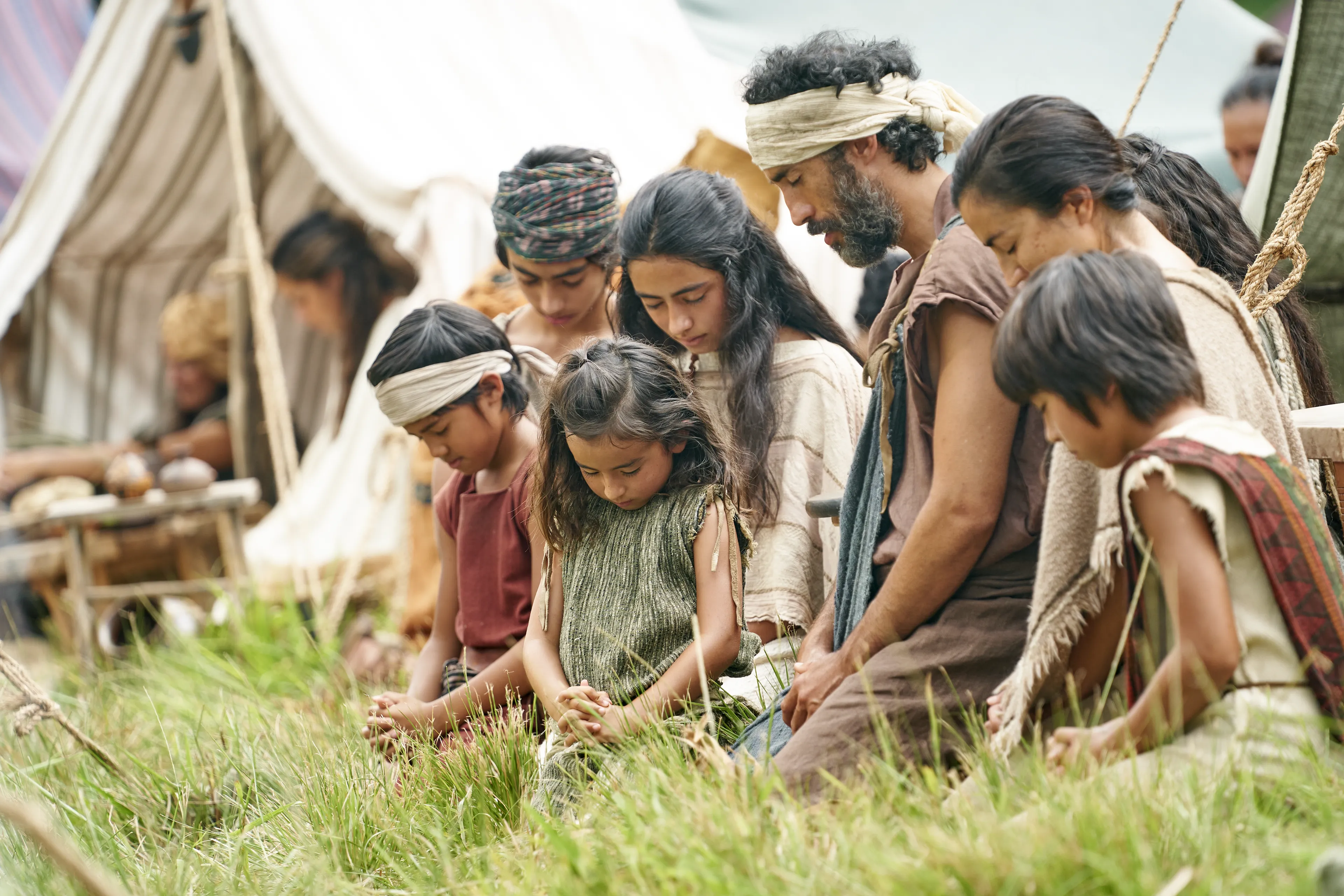 Families gather and kneel as they listen to King Benjamin in the Land of Zarahemla.