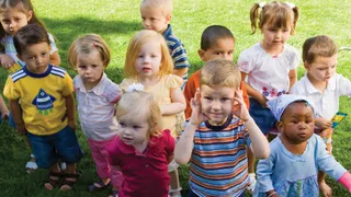A group of little boys and girls play together outside.
