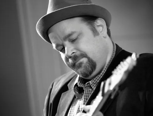 Black and white photograph of a man playing a guitar.