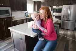 A mom holding her young daughter in the kitchen